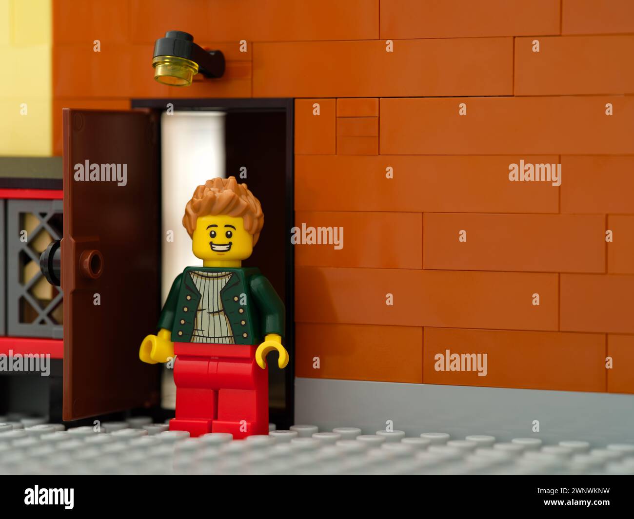 Tambov, Federazione Russa - 17 febbraio 2024 Una minifigura Lego uomo in piedi dietro un edificio vicino a una porta aperta Foto Stock
