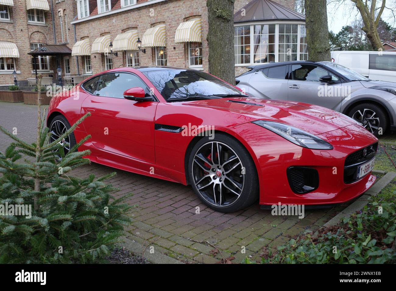 Sluis, Paesi Bassi - febbraio 27 2024 Una Jaguar F-Type rossa parcheggiata di fronte a un vecchio monastero convertito in hotel Foto Stock