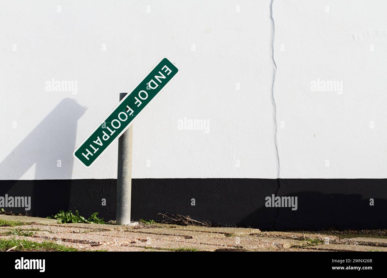 Wonky, Crooked, cartello della fine del sentiero pedonale contro Un muro bianco, Christchurch, Regno Unito Foto Stock