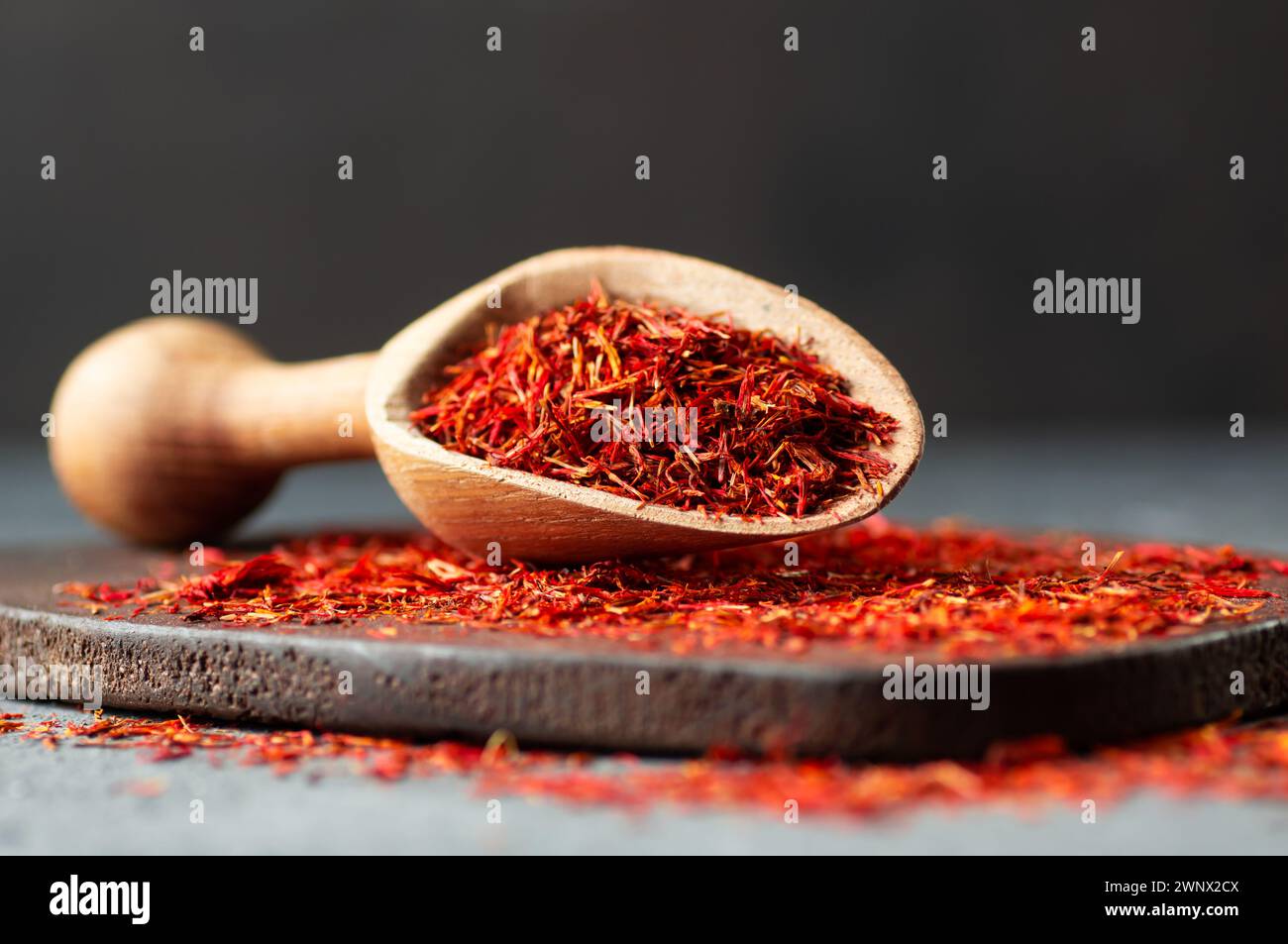 Macchie di zafferano essiccate in cucchiaio su fondo rustico, spezie ed erbe (Crocus sativus) Foto Stock