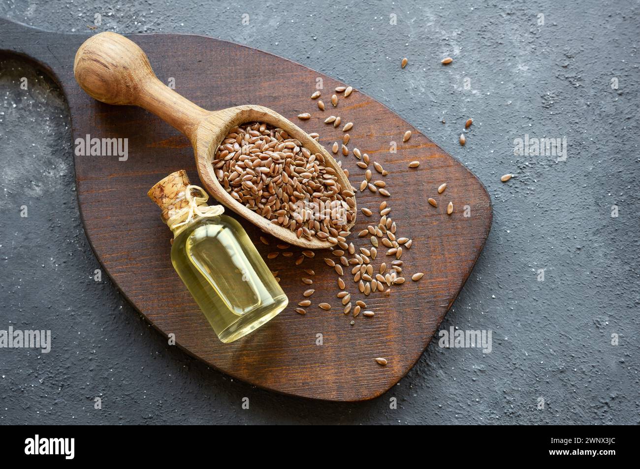 Bottiglia di vetro di semi di lino o olio di lino con semi di lino su tavola rustica, olio di fondo di fibra alimentare Foto Stock