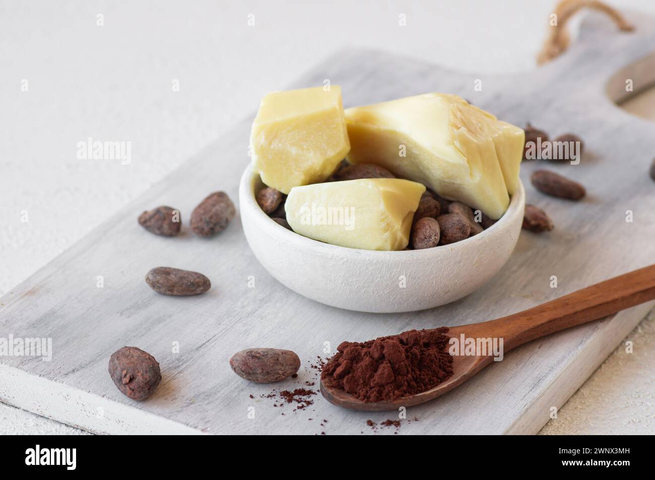 Burro di cacao o olio solido di fagioli di cacao e fagioli di cacao crudi sullo sfondo rustico, olio naturale sano Foto Stock