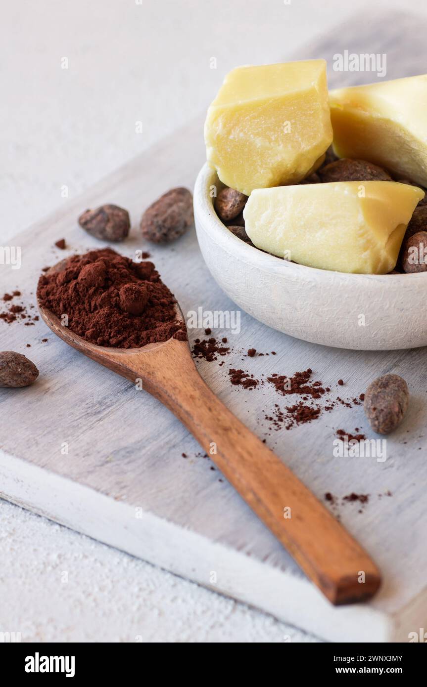 Burro di cacao o olio solido di fagioli di cacao e fagioli di cacao crudi sullo sfondo rustico, olio naturale sano Foto Stock
