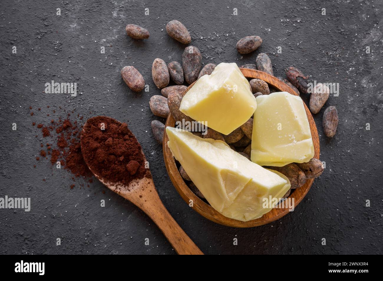 Burro di cacao o olio solido di fagioli di cacao e fagioli di cacao crudi sullo sfondo rustico, olio naturale sano Foto Stock