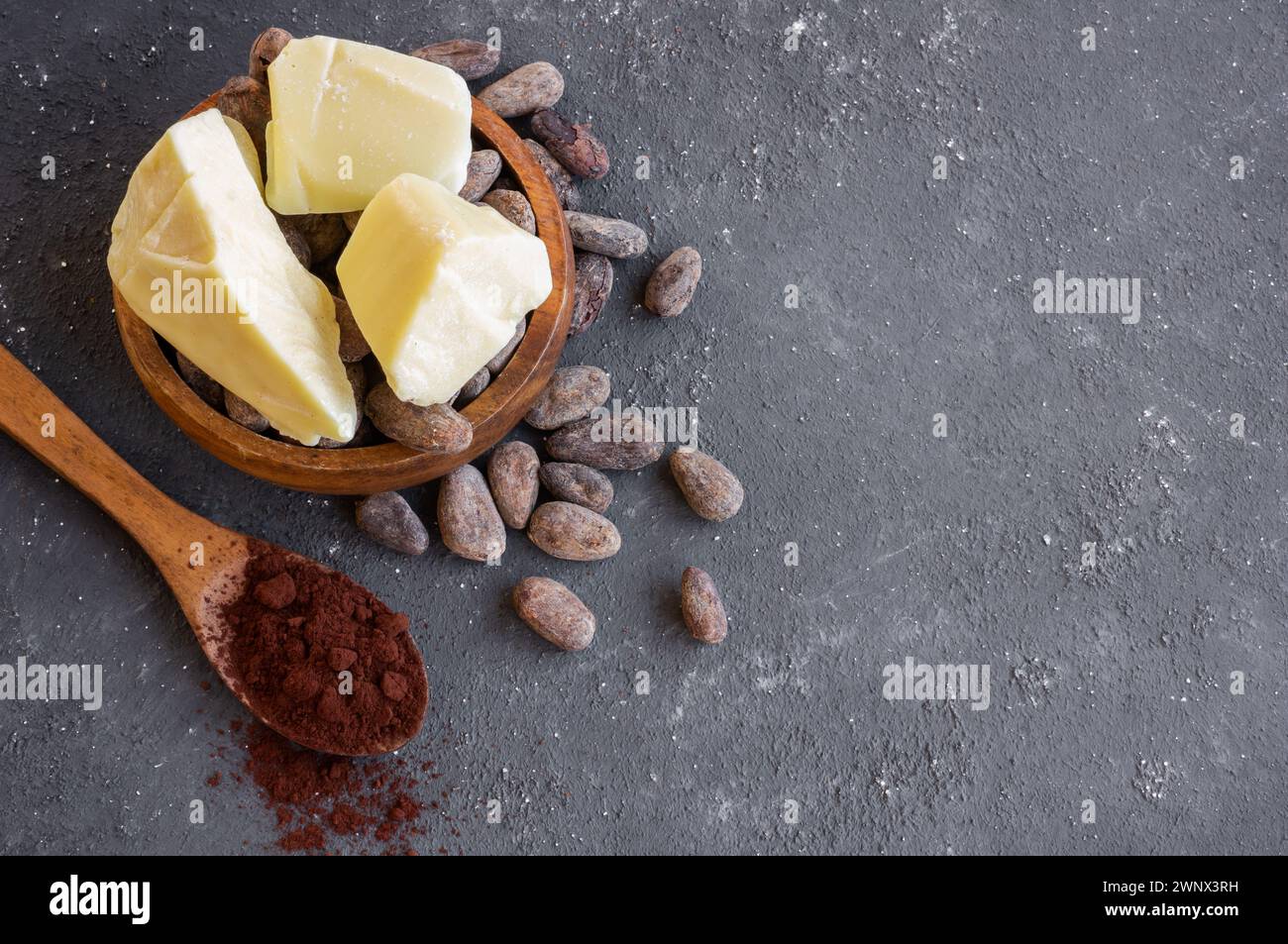 Burro di cacao o olio solido di fagioli di cacao e fagioli di cacao crudi sullo sfondo rustico, olio naturale sano Foto Stock