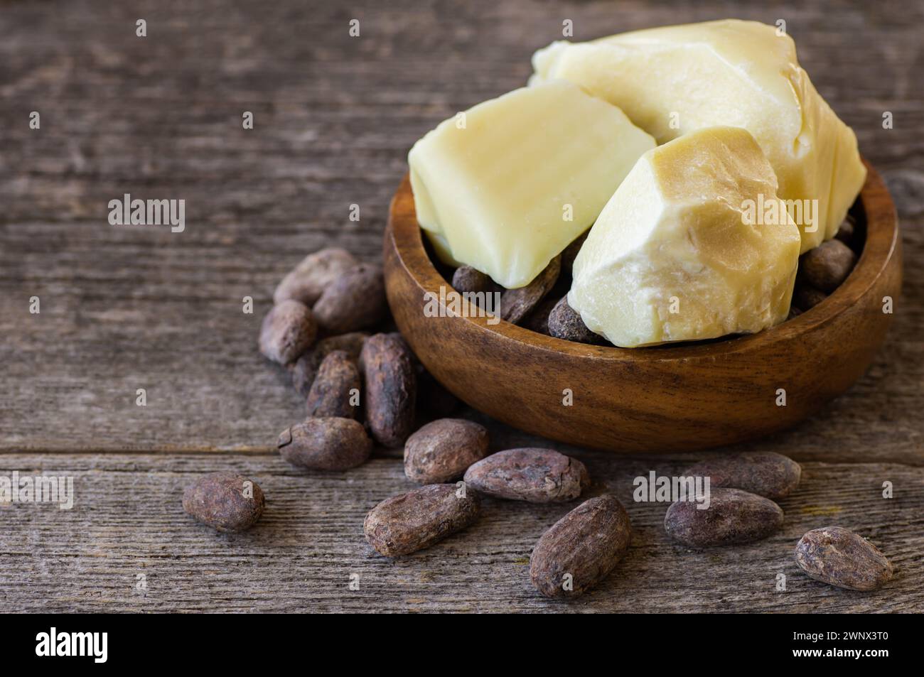 Burro di cacao o olio solido di fagioli di cacao e fagioli di cacao crudi sullo sfondo rustico, olio naturale sano Foto Stock