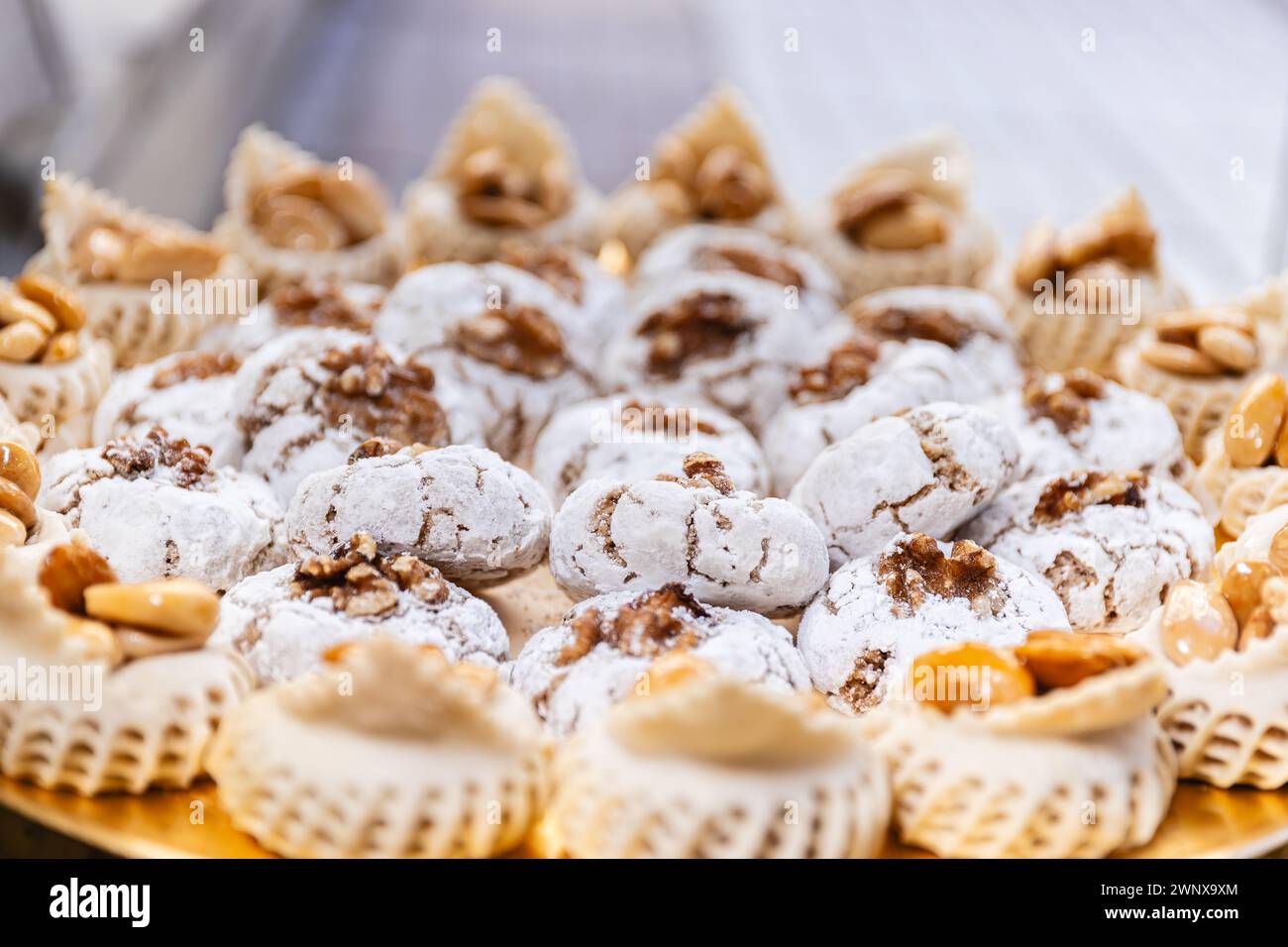 Foto orizzontale un primo piano di un piatto dorato pieno di dolci spolverati di noci, catturando l'essenza della pasticceria mediorientale durante le feste Foto Stock