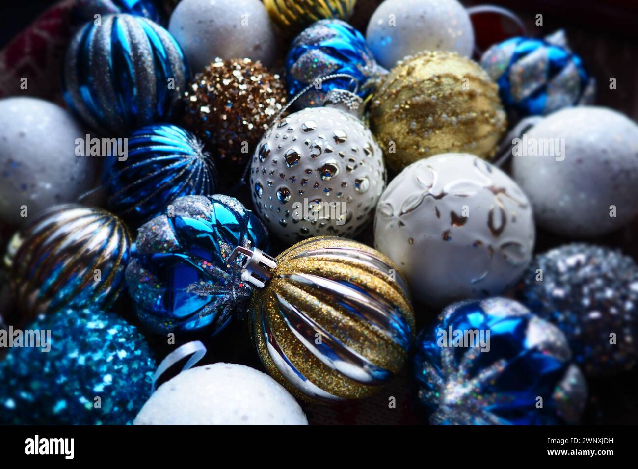 Le palle e le decorazioni di Natale di Capodanno da vicino. Molte decorazioni di oro, blu, giallo, bianco, argento. Le palle di Natale a righe sono aperte Foto Stock