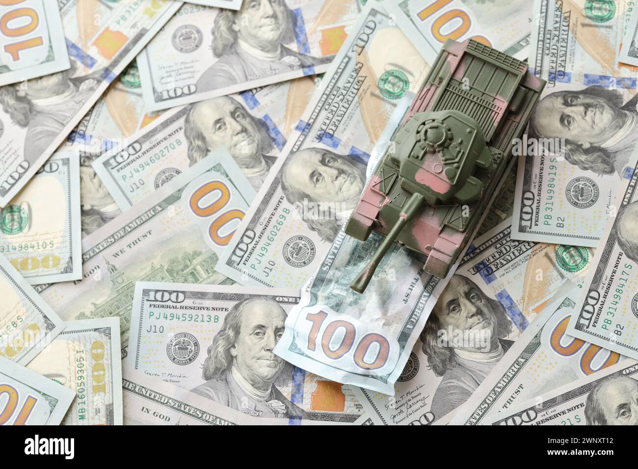 Carro armato su banconote da cento dollari schiacciate. Contesto del finanziamento di guerra e del prezzo di supporto militare per gli Stati Uniti d'America Foto Stock