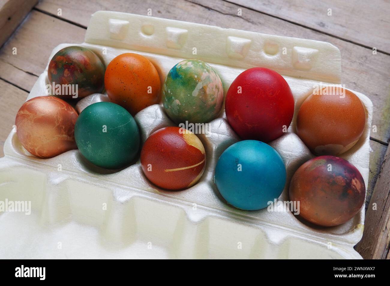 Le uova di Pasqua colorate si chiudono in una confezione di plastica. Dieci colorate uova natalizie sono impilate l'una vicino all'altra. Uova di pollo bollite con fiori e. Foto Stock