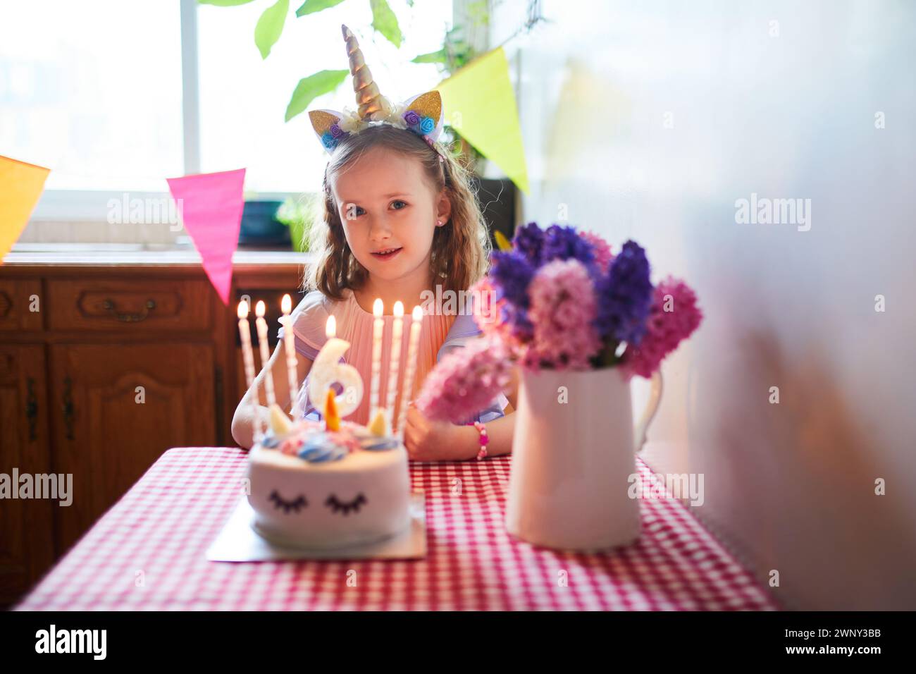 Bambina felice che festeggia il suo sesto compleanno e che esprime un desiderio. Ragazzino con torta di compleanno e candela. Foto Stock