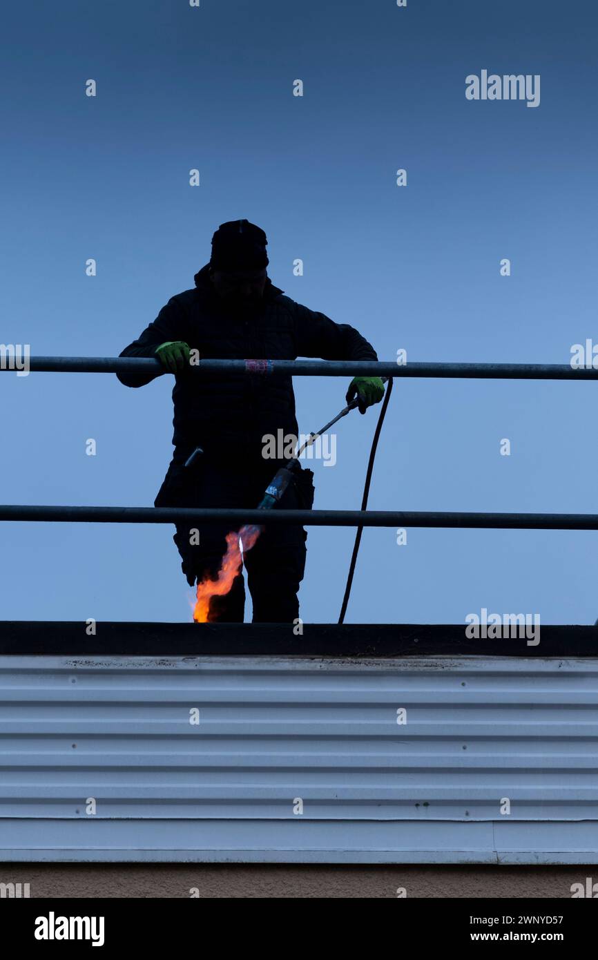 Uomo che installa feltro per tetti Foto Stock
