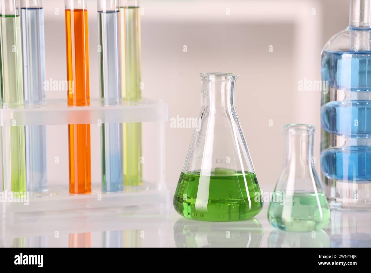 Analisi di laboratorio. Vetreria diversa con liquidi su tavolo bianco su sfondo sfocato Foto Stock