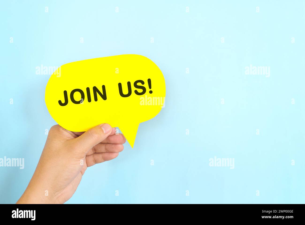 Mano umana che tiene la bolla gialla con una frase scritta Unisciti a noi o unisciti al nostro team. Concetto di assunzione e assunzione di lavoro. Foto Stock