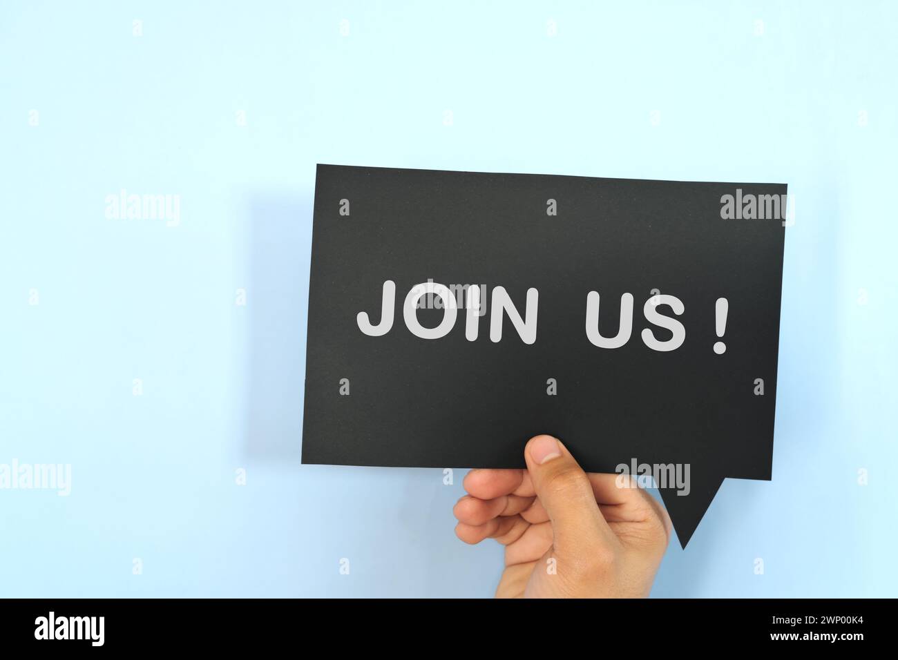 Mano umana che tiene la bolla gialla con una frase scritta Unisciti a noi o unisciti al nostro team. Concetto di assunzione e assunzione di lavoro. Foto Stock
