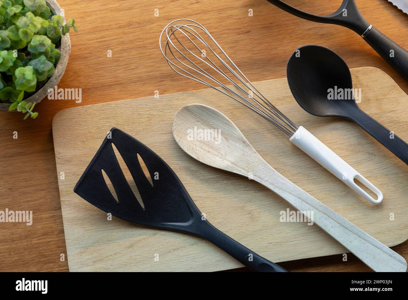 Utensili da cucina su un tagliere in legno che offrono funzionalità per le attività di preparazione degli alimenti. Foto Stock