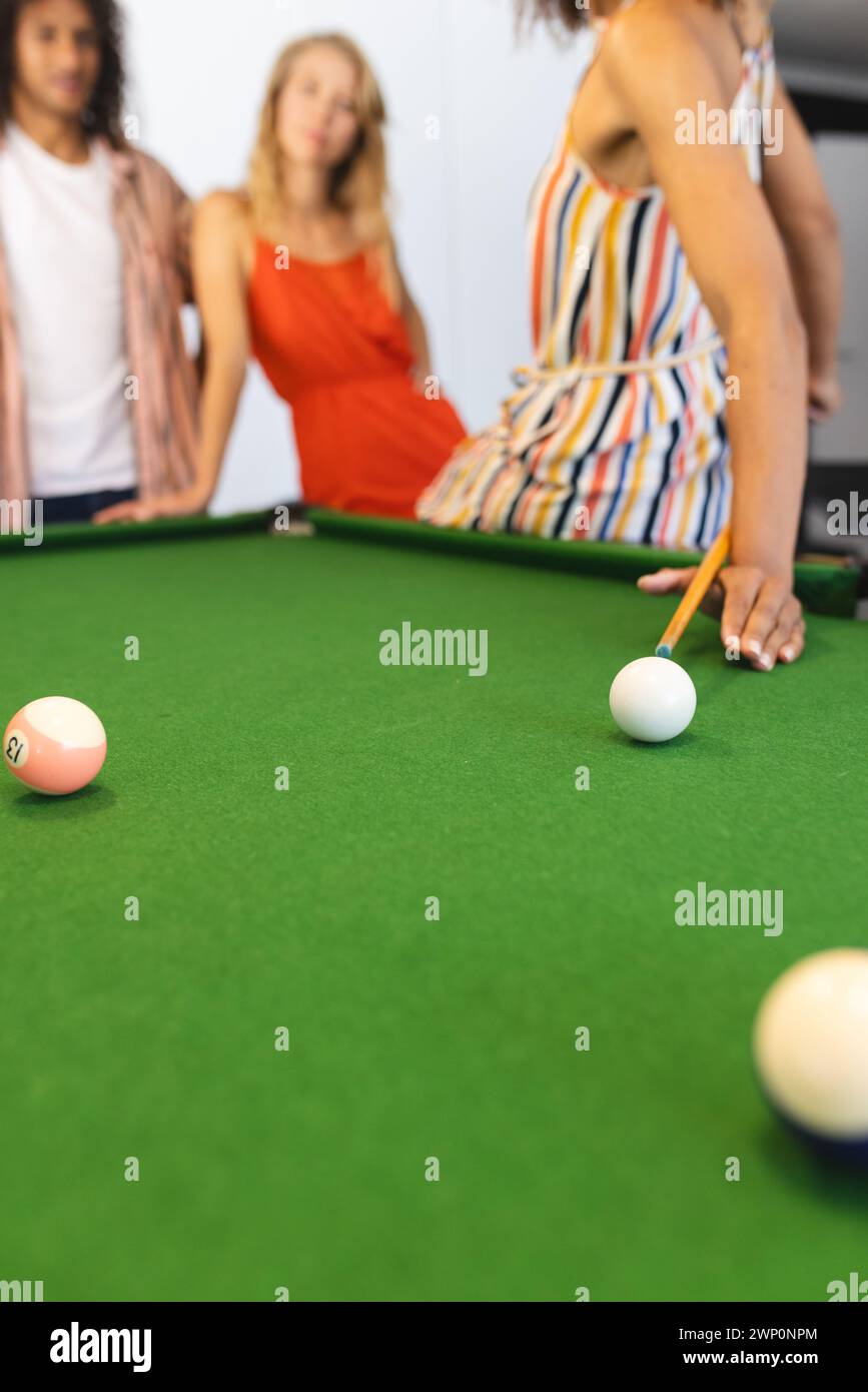 La concentrazione è su un tavolo da biliardo con le palle in una configurazione di gioco, con una donna che scatta un colpo Foto Stock