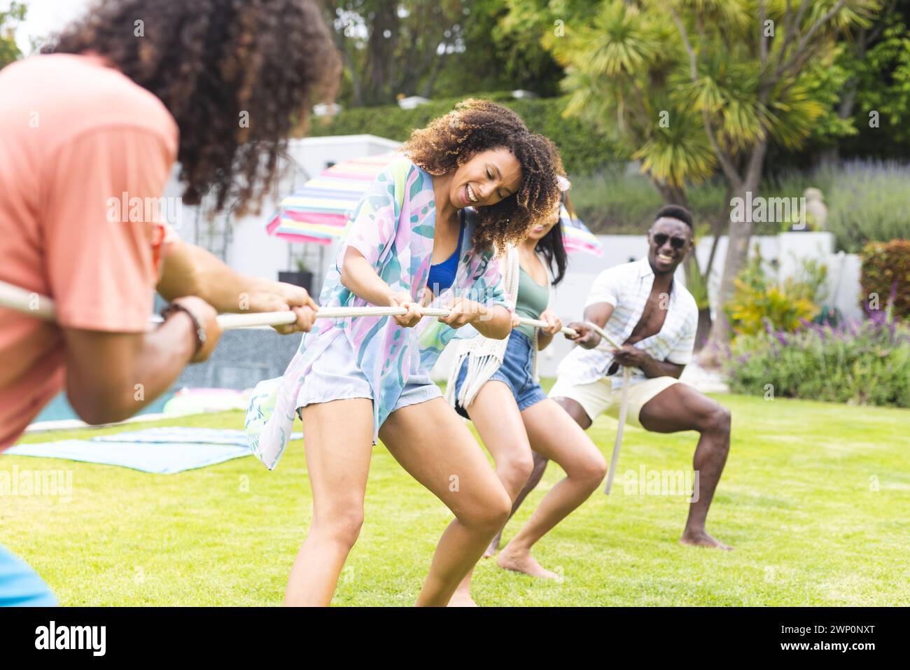 Gruppi diversi di amici si divertono con un tiro alla fune in una giornata di sole all'aperto Foto Stock
