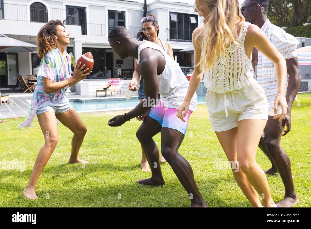 Gruppi diversi di amici si divertono a giocare a calcio in un cortile soleggiato Foto Stock