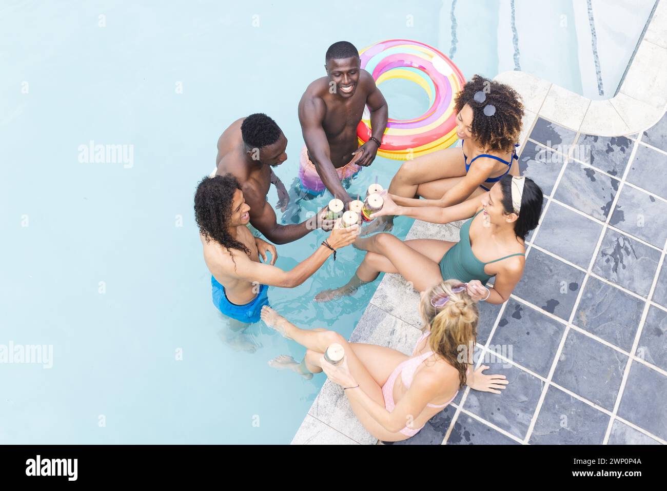 Gruppi diversi di amici che si godono una festa in piscina, brindano con bevande Foto Stock