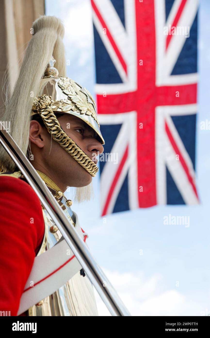 Regno Unito, Londra, un membro a cavallo del Royal Horse Guards Regiment in servizio di sentinella fuori Horse Guards Whitehall, Londra, Inghilterra con la bandiera dell'Unione Foto Stock