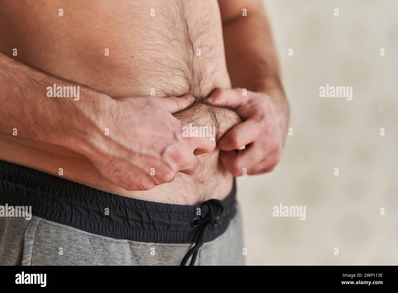 eccesso di grasso sullo stomaco di un giovane uomo Foto Stock