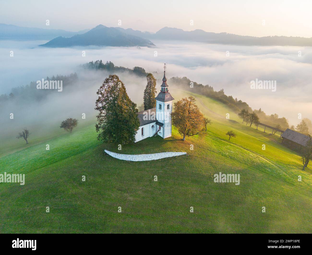 Chiesa di Sveti Tomaž in Slovenia in una mattina nebbiosa Foto Stock