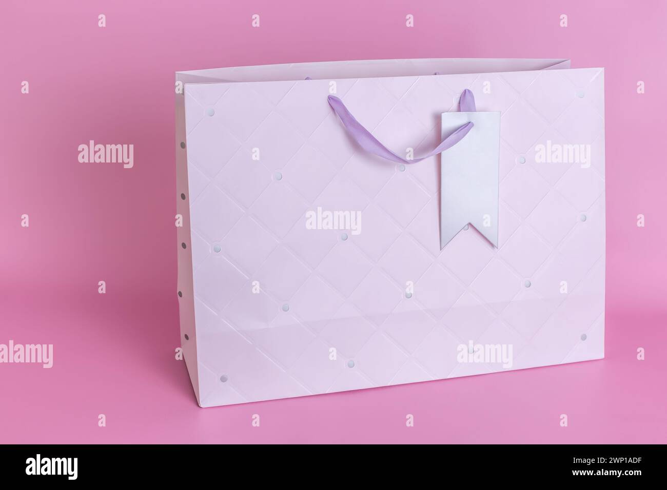 Un sacchetto di carta grande e pulito con manici si trova su uno sfondo rosa in primo piano. Foto Stock