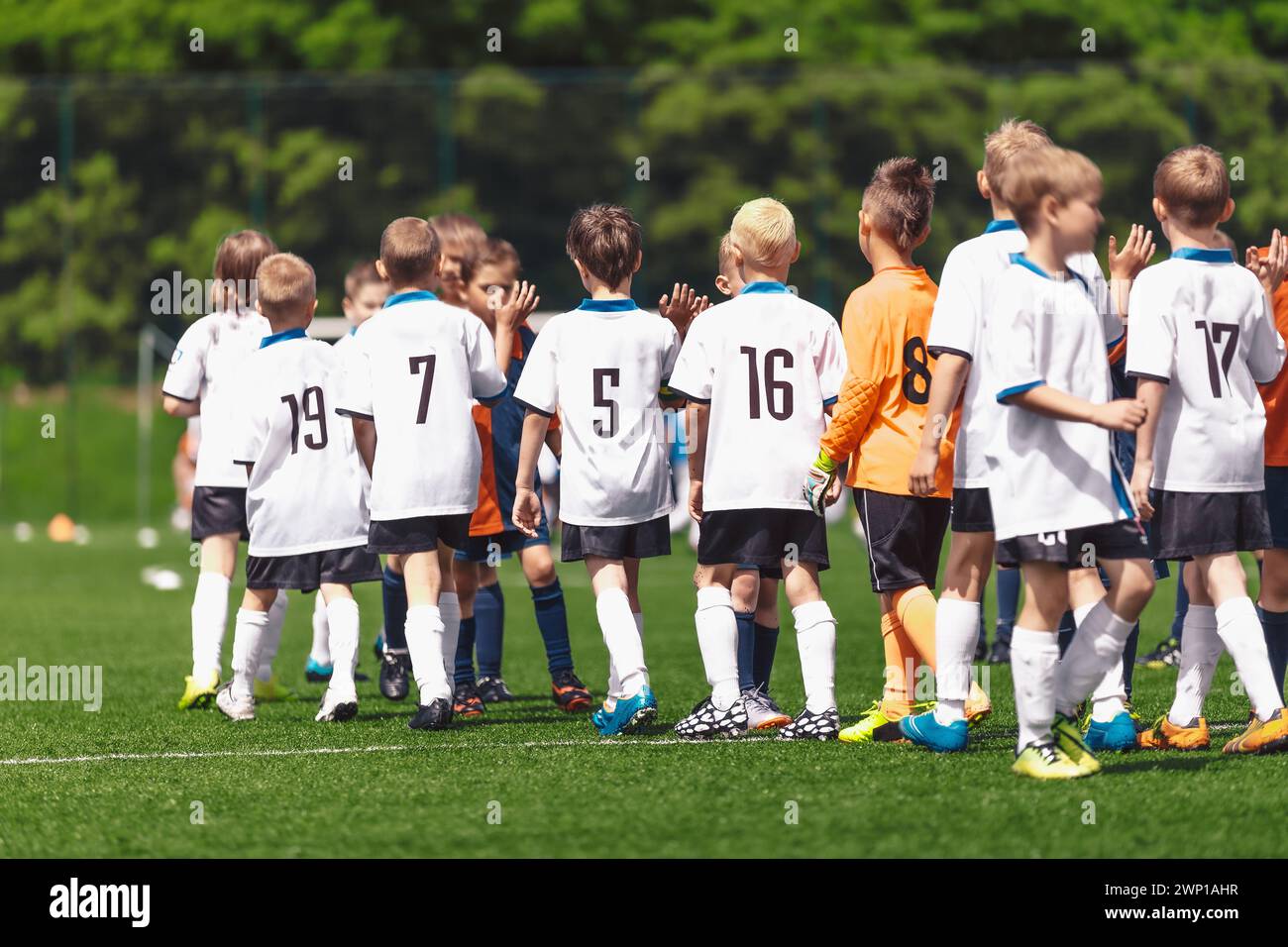 I ragazzi giocatori di calcio si ringraziano a vicenda per aver giocato dopo la fine della competizione. I bambini giocano a sport su un campo di erba. Football bambini fair play Behavior af Foto Stock