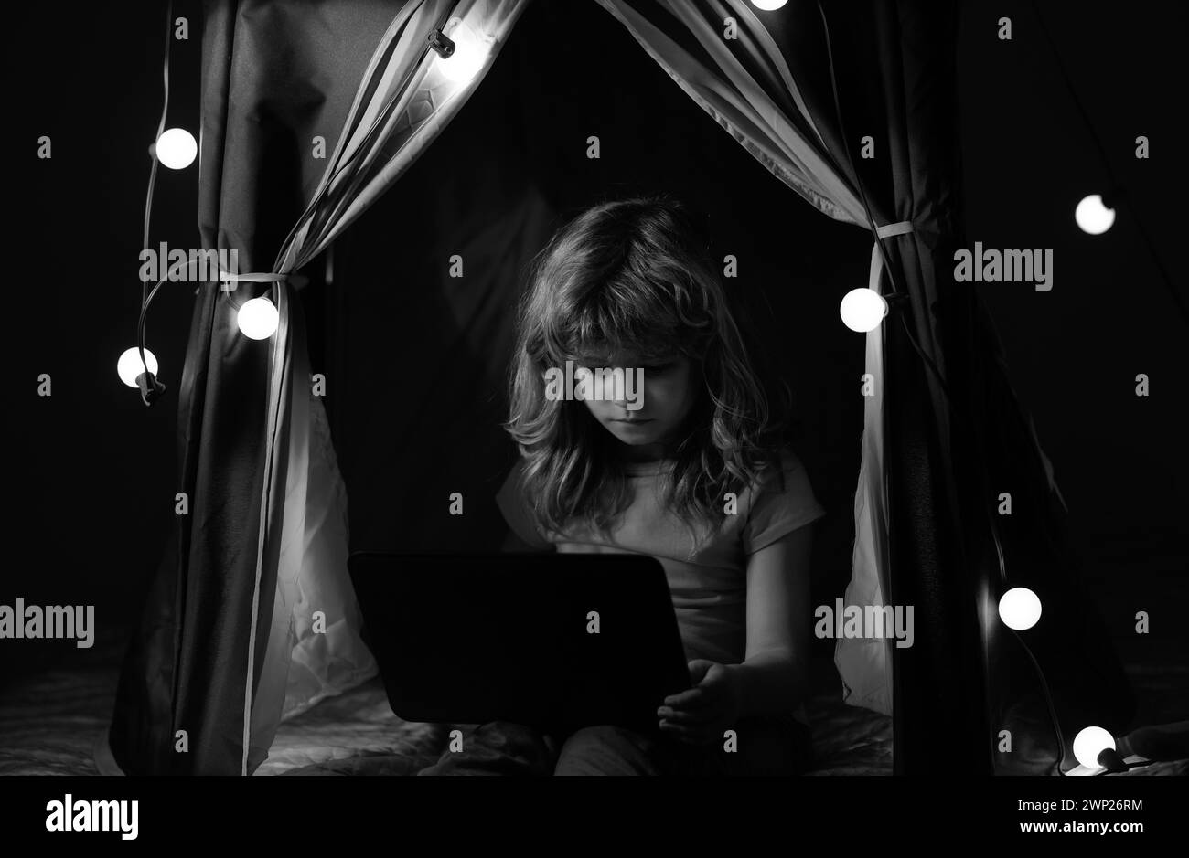Il bambino si annoia al computer di notte al buio. I bambini di overuse e di dipendenza dai gadget. Foto Stock
