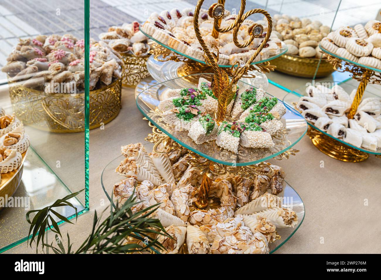 Foto orizzontale un sontuoso spettacolo di dolci arabi, caratterizzato da una varietà di texture e sapori, presentati su squisiti banchi dorati con intricati piatti Foto Stock