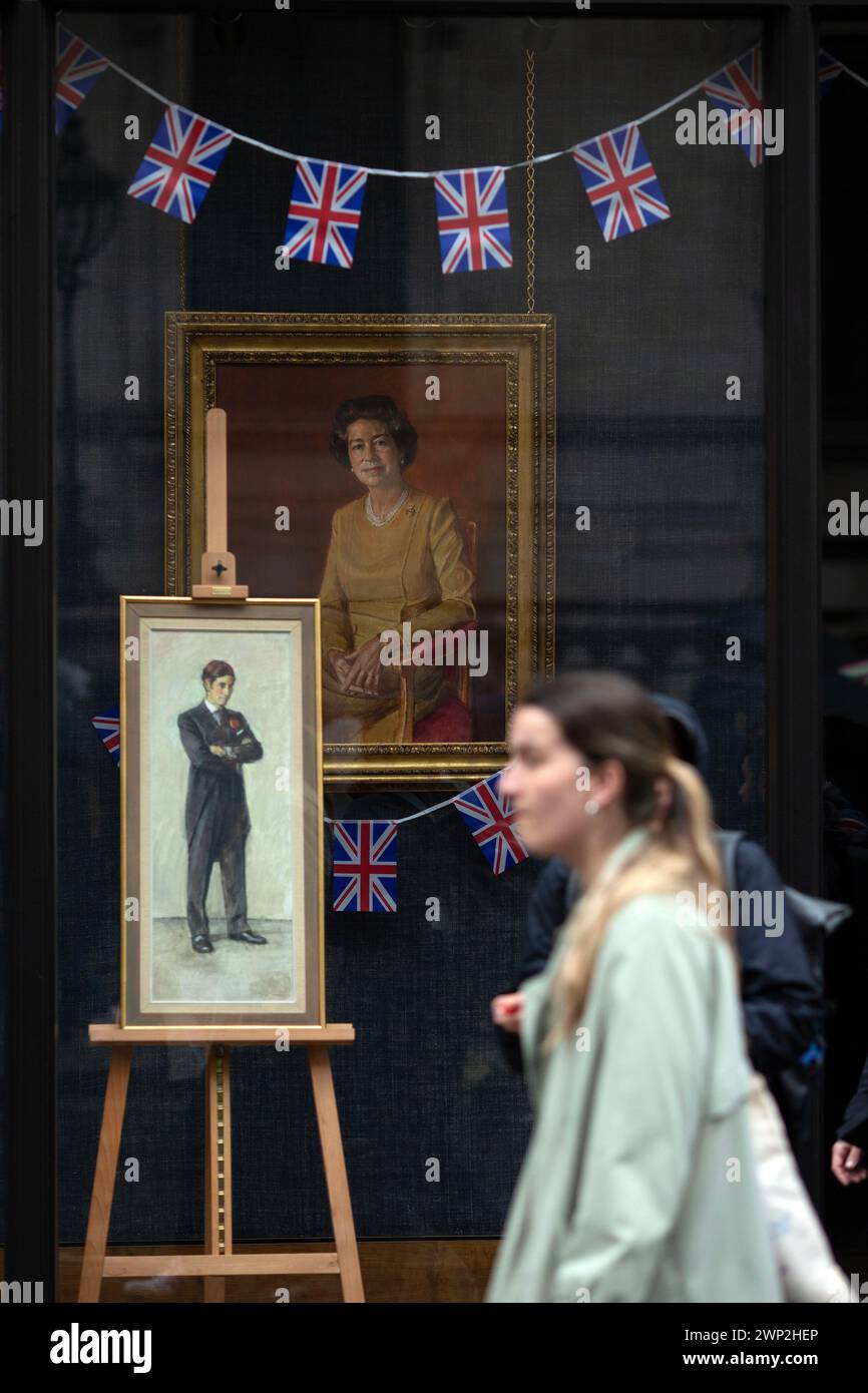 I ritratti di re Carlo III e della defunta regina Elisabetta II sono visti in una vetrina mentre le persone si riuniscono per vedere l'incoronazione del re a Londra. Foto Stock