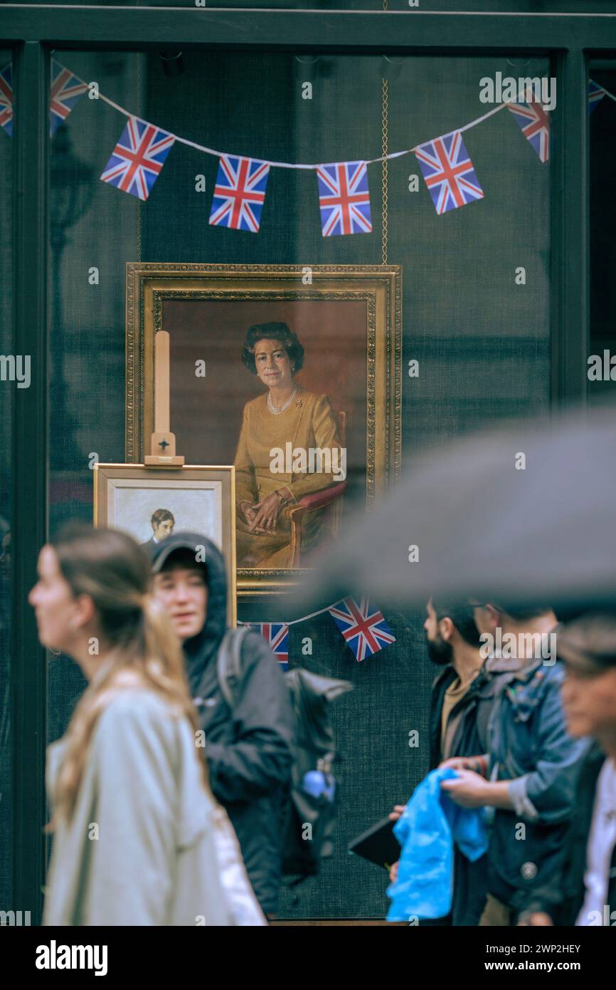 I ritratti di re Carlo III e della defunta regina Elisabetta II sono visti in una vetrina mentre le persone si riuniscono per vedere l'incoronazione del re a Londra. Foto Stock