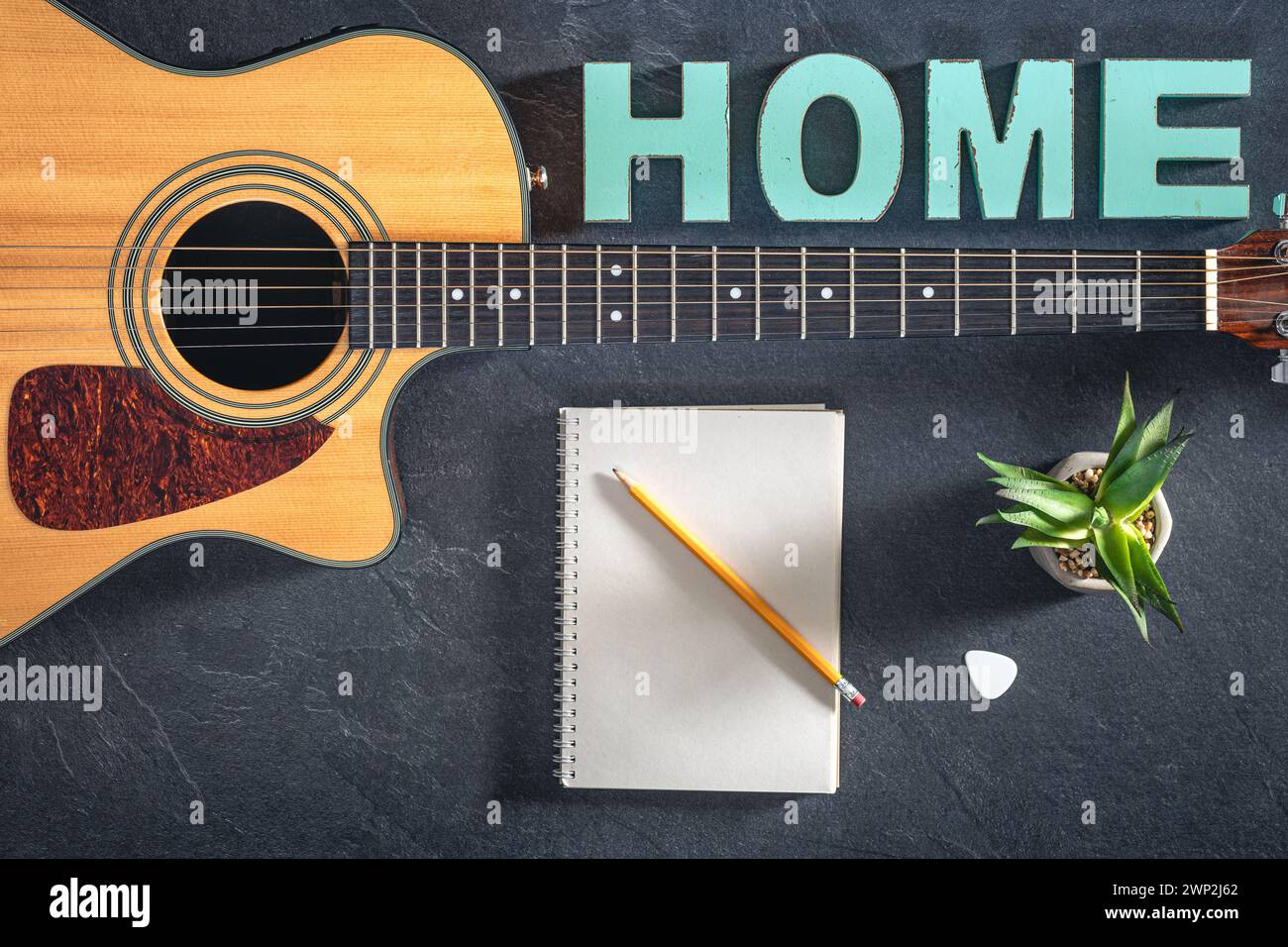 Chitarra acustica, blocco note e parola decorativa Home, vista dall'alto. Foto Stock