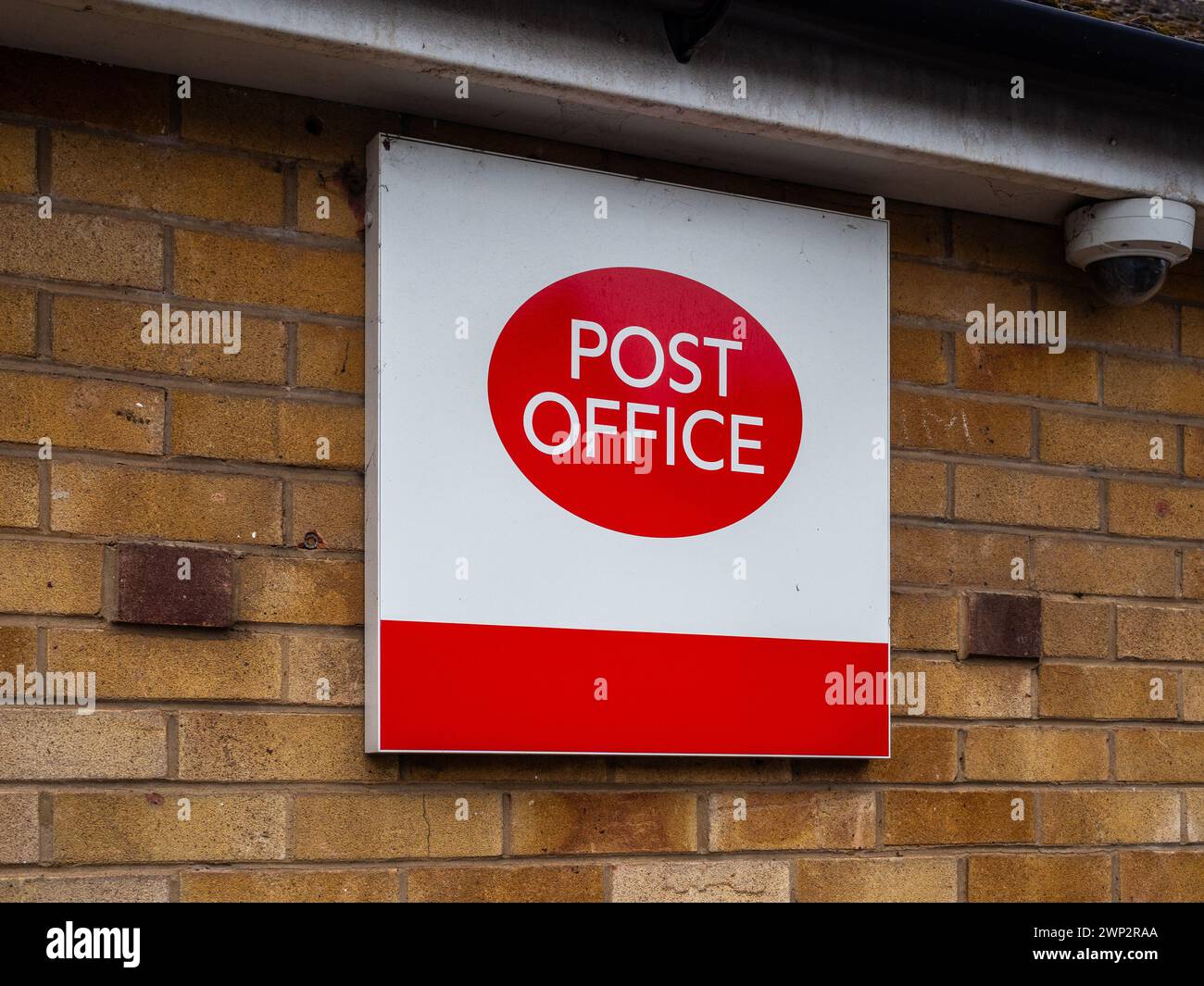 Cartello rosso e bianco dell'ufficio postale appeso fuori dalla filiale di un ufficio postale nel villaggio di Hardingstone, Northampton, Regno Unito Foto Stock