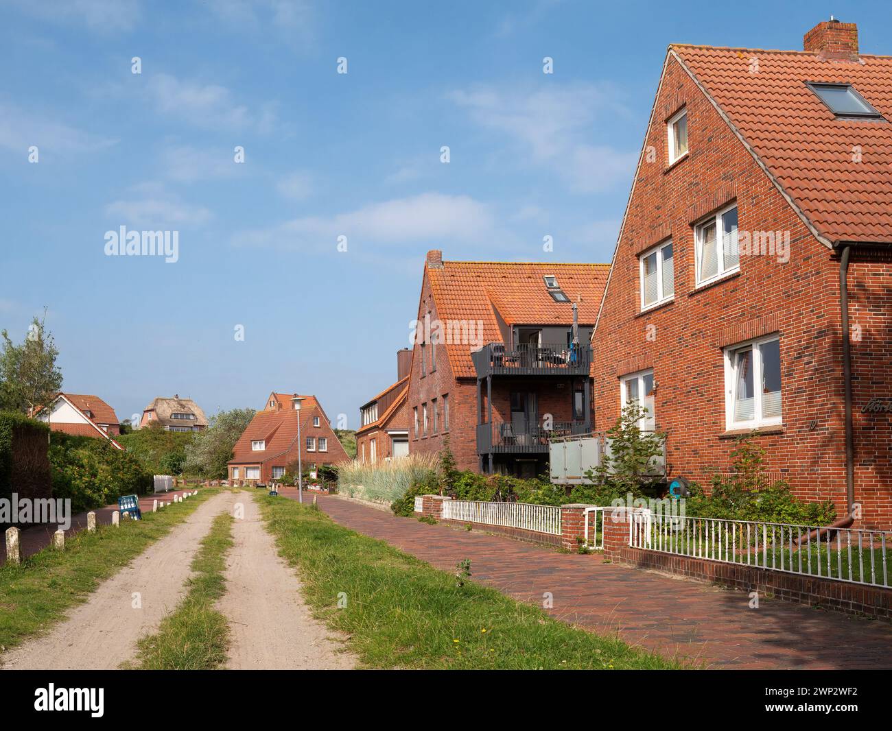 Scena di strada con strada sterrata e case nel villaggio dell'isola della Frisia orientale Juist, bassa Sassonia, Germania Foto Stock