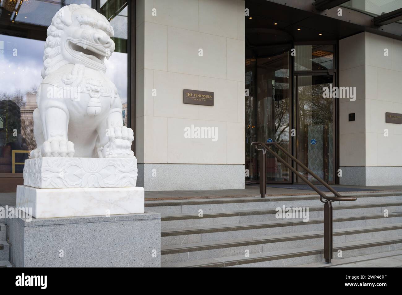 Ingresso principale al Peninsula Hotel a 5 stelle affiancato dalla statua cinese del leone guardiano. Hyde Park Corner Belgravia Londra Inghilterra Regno Unito Foto Stock