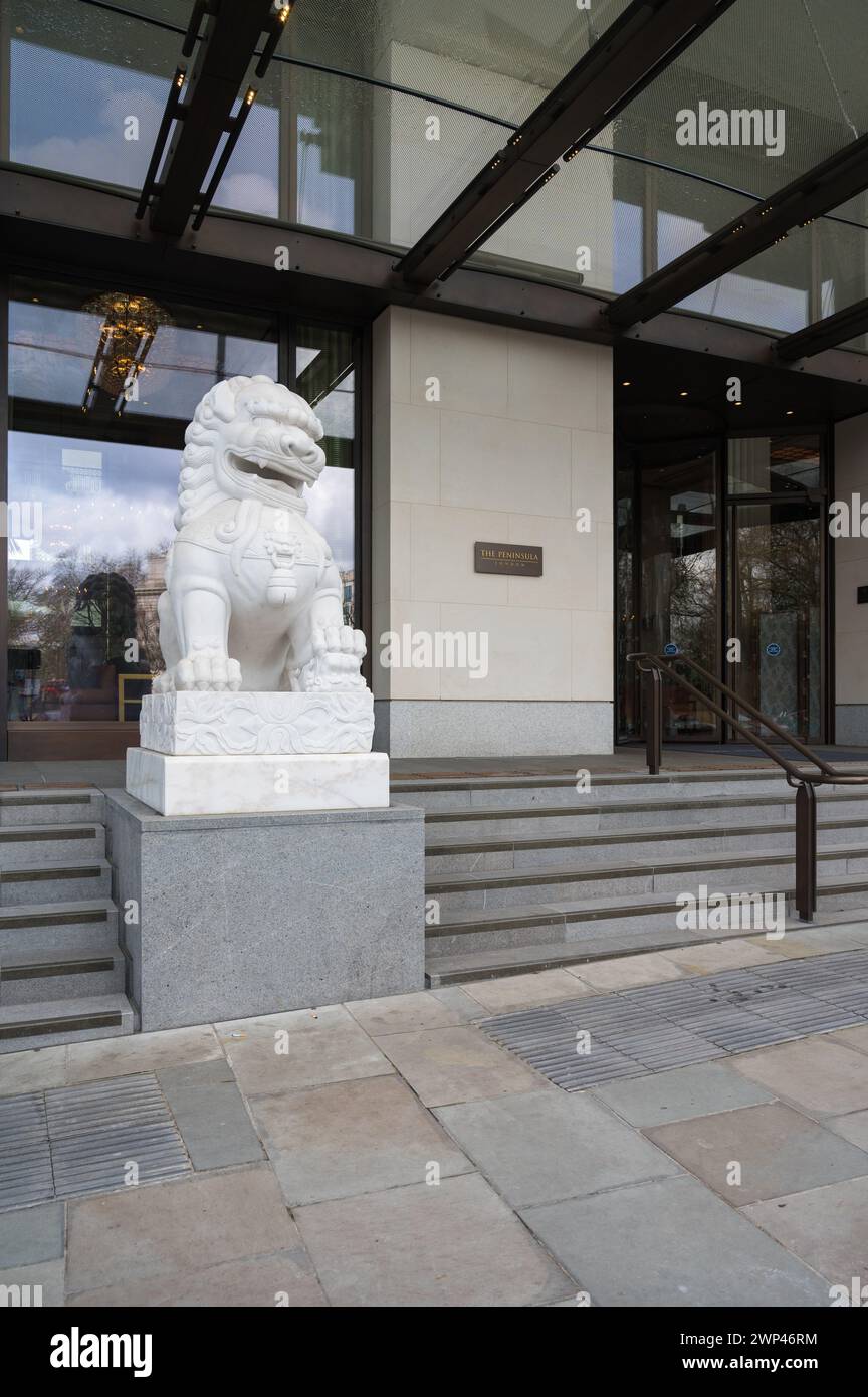 Ingresso principale al Peninsula Hotel a 5 stelle affiancato dalla statua cinese del leone guardiano. Hyde Park Corner Belgravia Londra Inghilterra Regno Unito Foto Stock