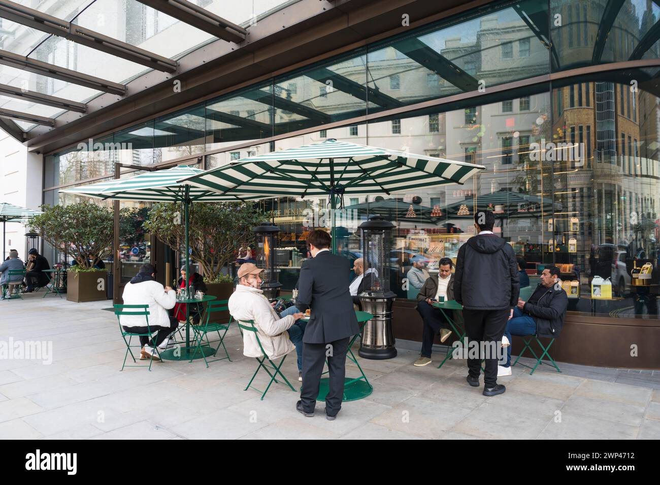 Le persone sedute ai tavoli del marciapiede prendono rinfreschi fuori dal Boutique and Cafe del Peninsula Hotel. Grosvenor Crescent Belgravia Londra, Inghilterra Foto Stock