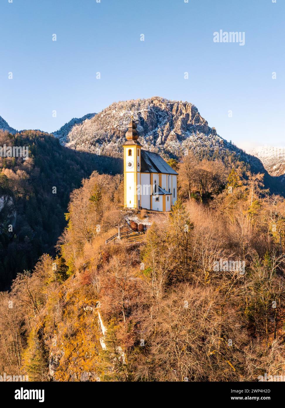 Chiesa isolata nella neve con un cielo azzurro e le montagne, St Pankraz, Karlstein, Bad Reichenhall, Germania Foto Stock