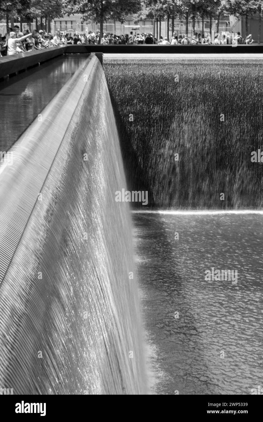 Una foto in bianco e nero dell'acqua a cascata al 9/11 Memorial di New York City, con gli edifici circostanti riflessi nell'acqua. Foto Stock