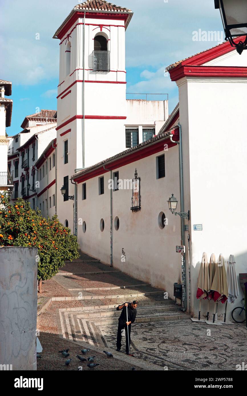Il quartiere di Albaicín, Granada, Spagna. Un uomo spazia l'area acciottolata di fronte all'Iglesia de San Gregorio con la sua torre di chiesa simile a un minareto. Foto Stock