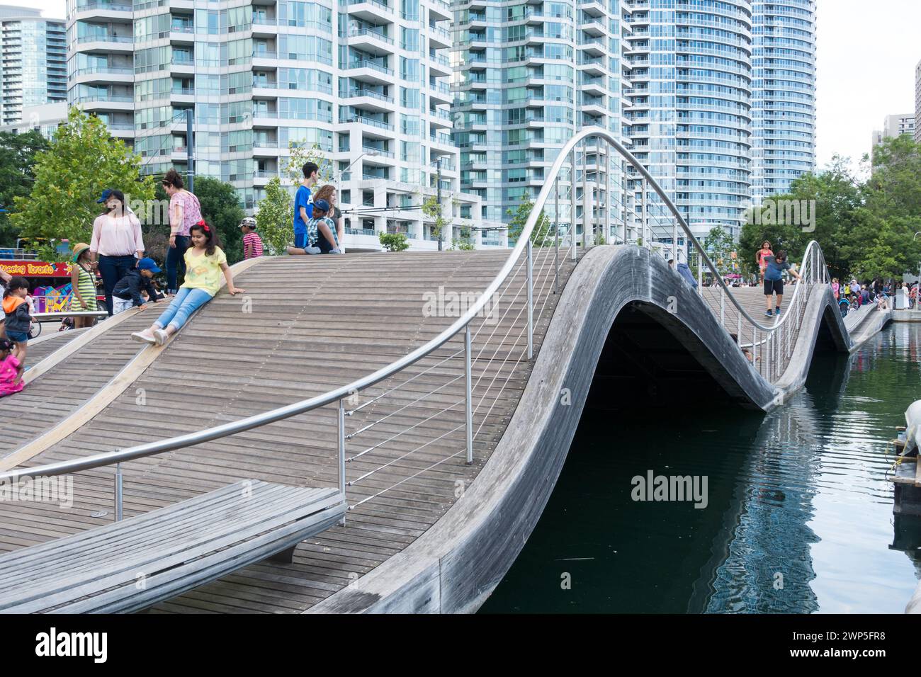 I turisti e i pedoni tentano di camminare sul Simcoe Wave Deck, un esempio fantasioso di arte urbana a Harbourfront nel centro di Toronto, Ontario. Foto Stock