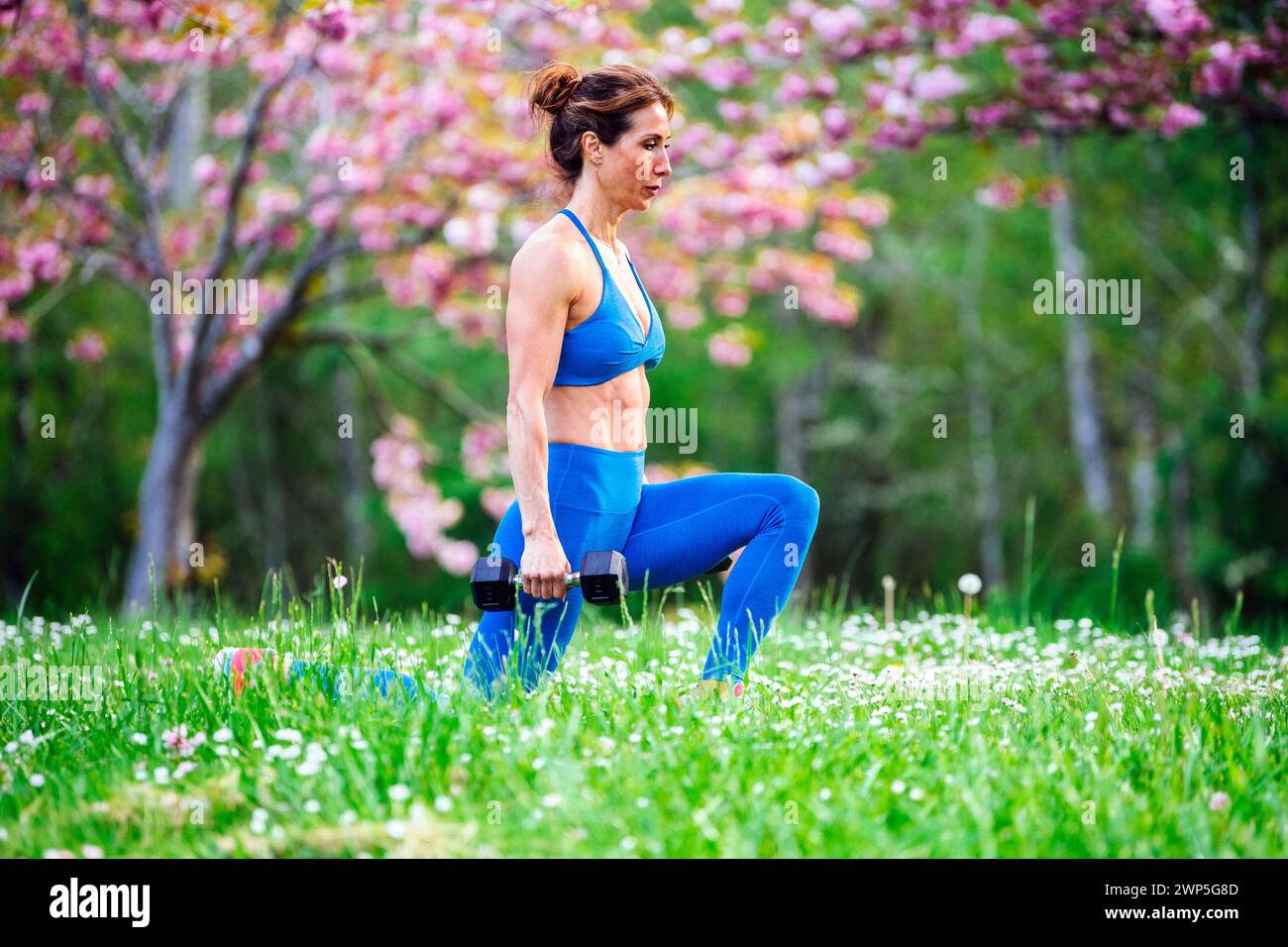 Atleta che si allena indossando abbigliamento sportivo tra i ciliegi Foto Stock