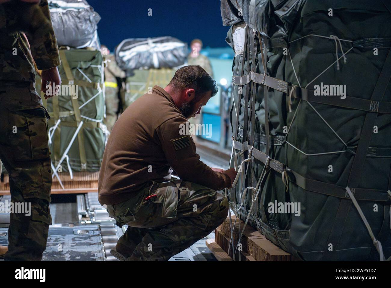 Washington, Stati Uniti. 4 marzo 2024. Gli aviatori della U.S. Air Force e i soldati dell'esercito statunitense preparano pacchetti di assistenza umanitaria per il lancio aereo a bordo di un C-130J Super Hercules della U.S. Air Force in un luogo non divulgato all'interno dell'area di responsabilità dello U.S. Central Command, martedì 5 marzo 2024. L'assistenza umanitaria comprende 60 pallet, composti da oltre 36.800 pasti, destinati a Gaza per fornire cibo e sostentamento ai civili colpiti dal conflitto in corso nella regione. Foto tramite U.S. Air Force Courtesy/UPI Credit: UPI/Alamy Live News Foto Stock Washington, Stati Uniti. 4 marzo 2024. Gli aviatori della U.S. Air Force e i soldati dell'esercito statunitense preparano pacchetti di assistenza umanitaria per il lancio aereo a bordo di un C-130J Super Hercules della U.S. Air Force in un luogo non divulgato all'interno dell'area di responsabilità dello U.S. Central Command, martedì 5 marzo 2024. L'assistenza umanitaria comprende 60 pallet, composti da oltre 36.800 pasti, destinati a Gaza per fornire cibo e sostentamento ai civili colpiti dal conflitto in corso nella regione. Foto tramite U.S. Air Force Courtesy/UPI Credit: UPI/Alamy Live News Foto Stock