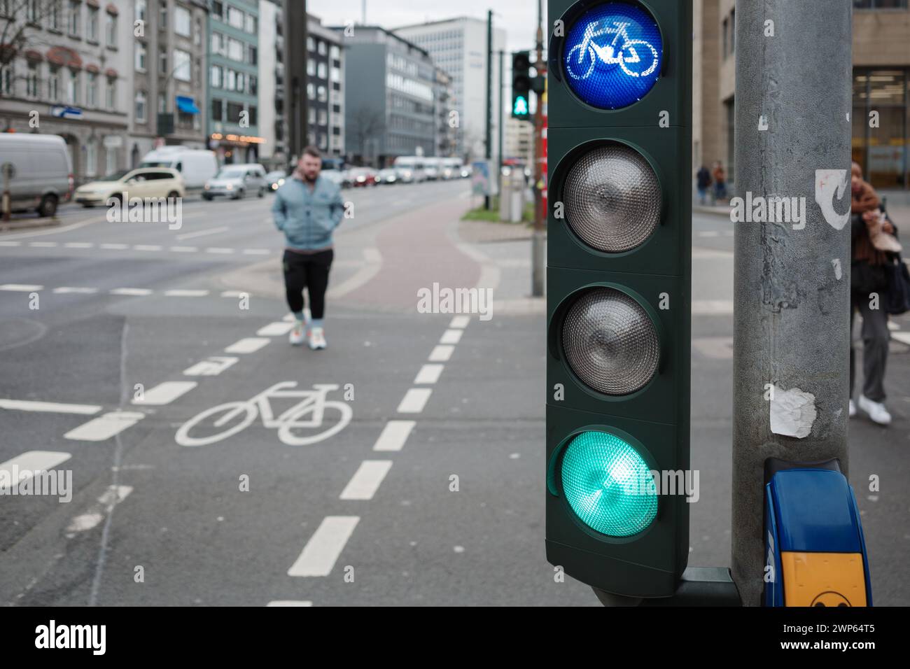 Il vivace segnale LED della bicicletta si contrappone alla sfocatura di un incrocio cittadino e di una pista ciclabile affollati. Foto Stock