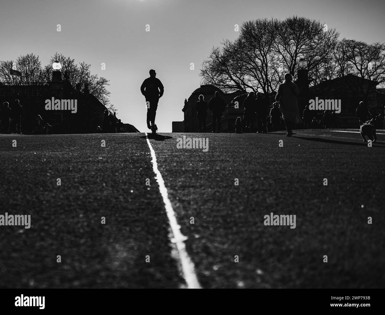 silhouette di un uomo su uno scooter che percorre una strada asfaltata Foto Stock