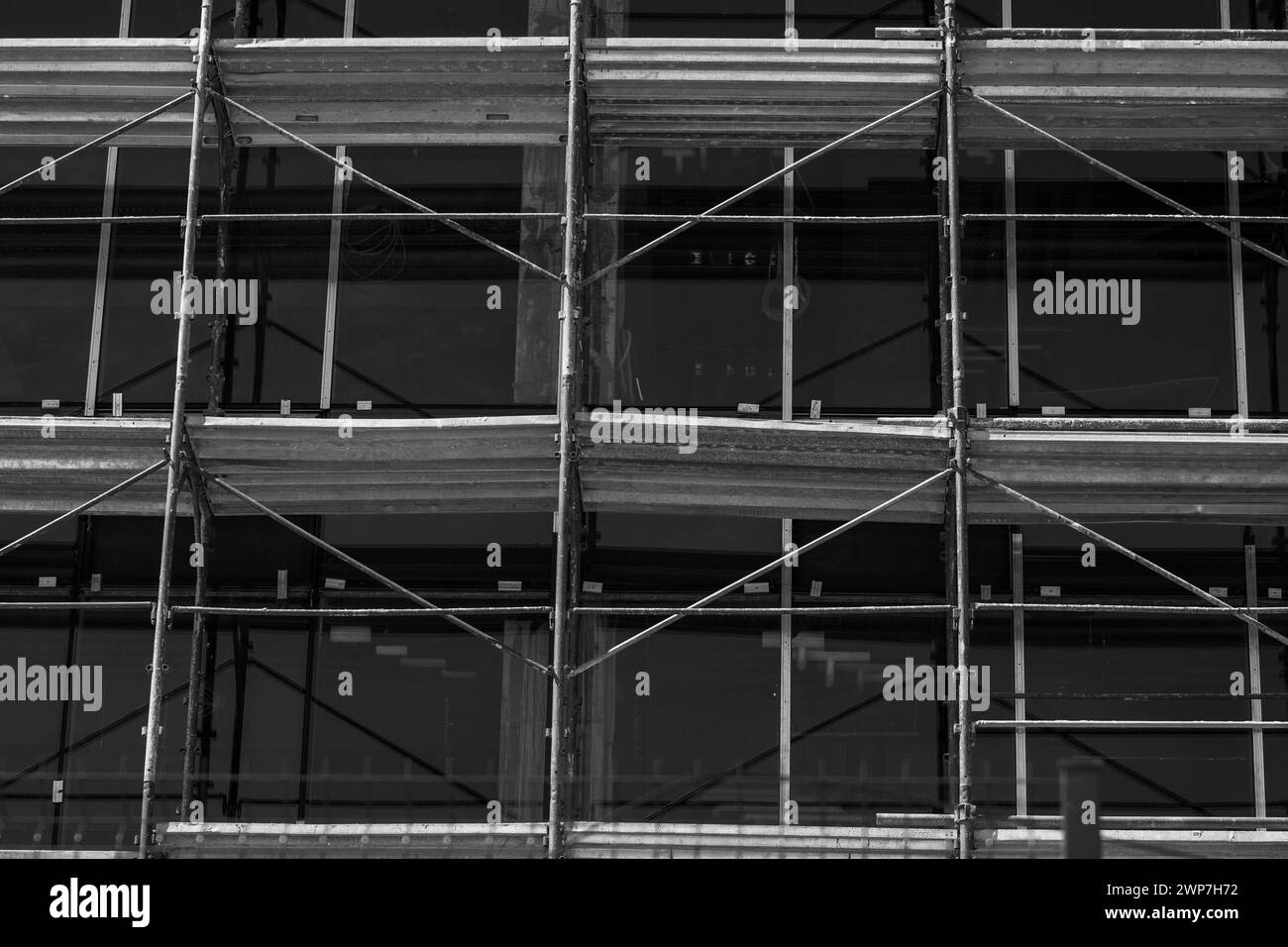 Edificio moderno in costruzione. Ponteggio, facciata in vetro, design esterno. Bianco e nero monocromatico. Foto Stock