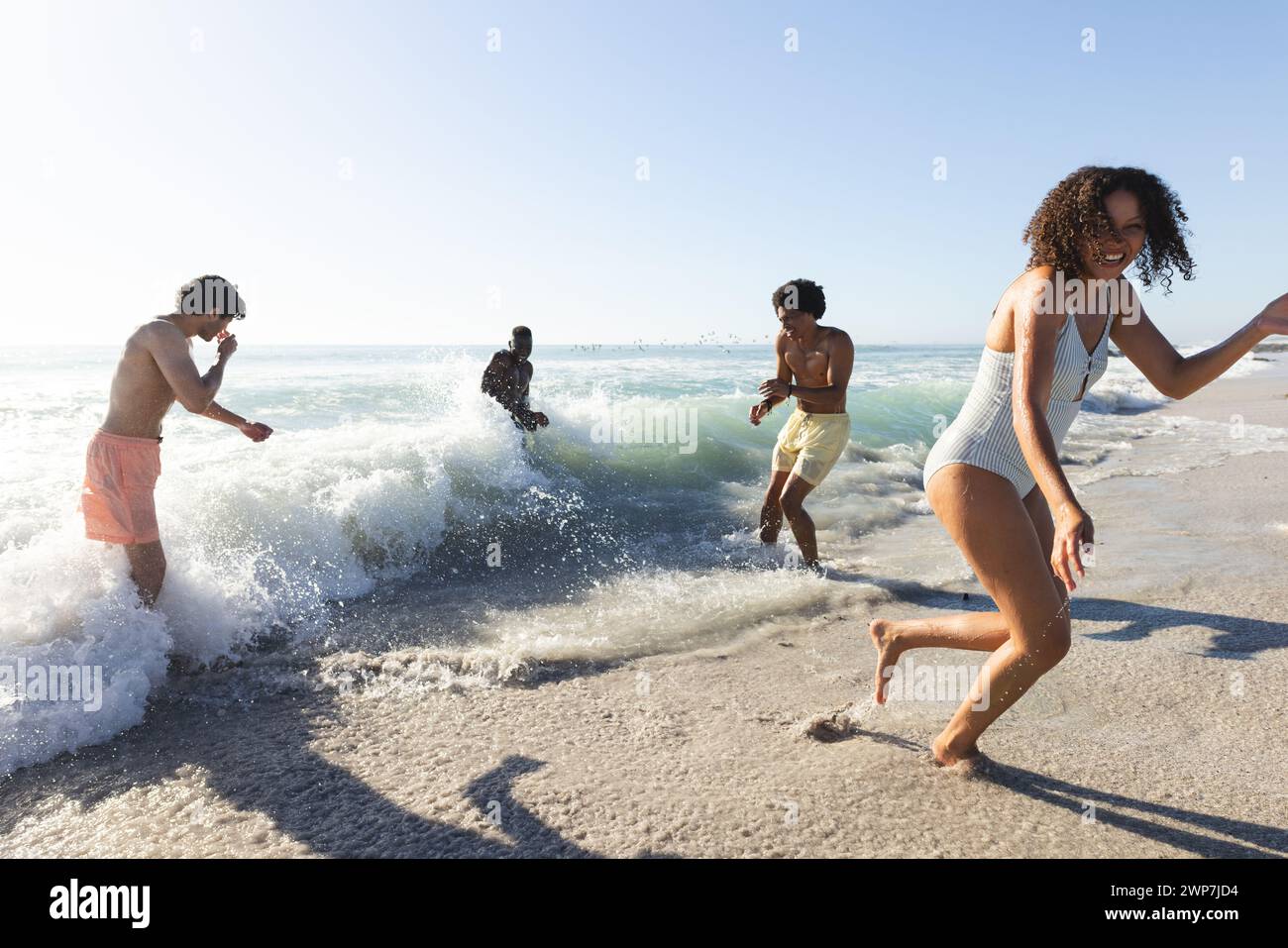 Giovani donne birazziali e diversi gruppi di amici si divertono in spiaggia Foto Stock