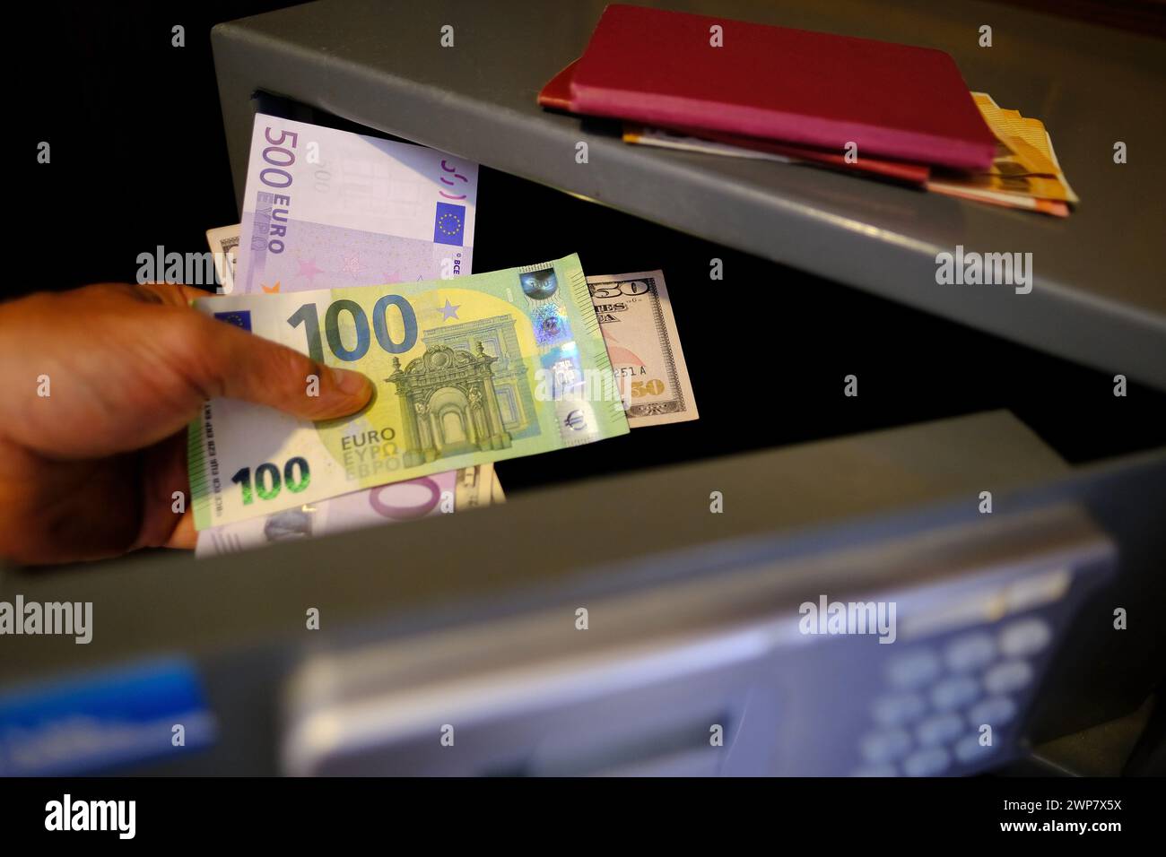 le mani maschili ravvicinate tengono 50 banconote da 500 euro dell'unione europea, documenti personali, il turista mette il denaro nella cassaforte dell'hotel con serratura elettronica, concetto Foto Stock